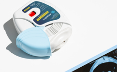 Close-up of an Altanine Sumatriptan inhalation device with a light blue mouthpiece, resting on a white surface beside a partially visible brain scan image, representing innovative migraine treatment delivery.